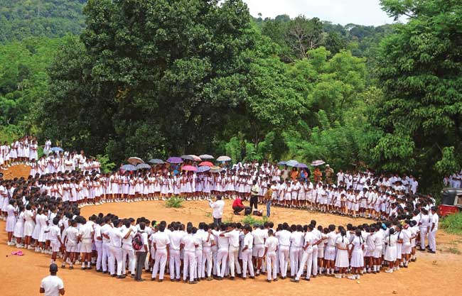 Uniformed students form a large circle outside to watch actors who perform a drama in the middle.