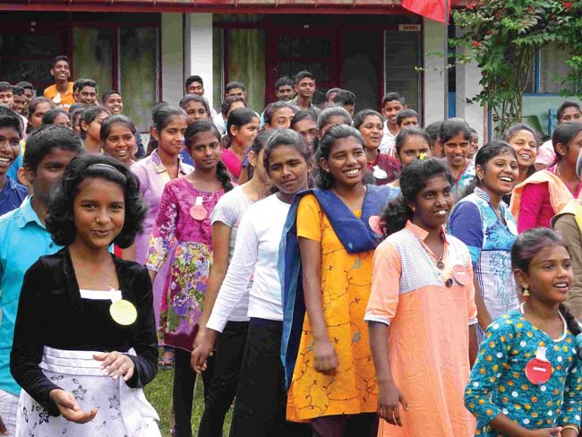 Smiling schoolgirls gather outside to watch the street drama team.